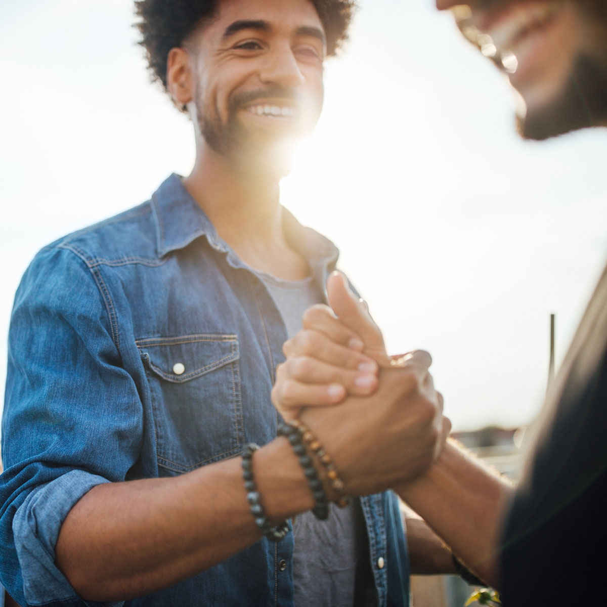 Two guys laughing and clasping each other's hand